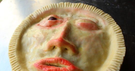 a woman's face is made out of pie crust on top of a table