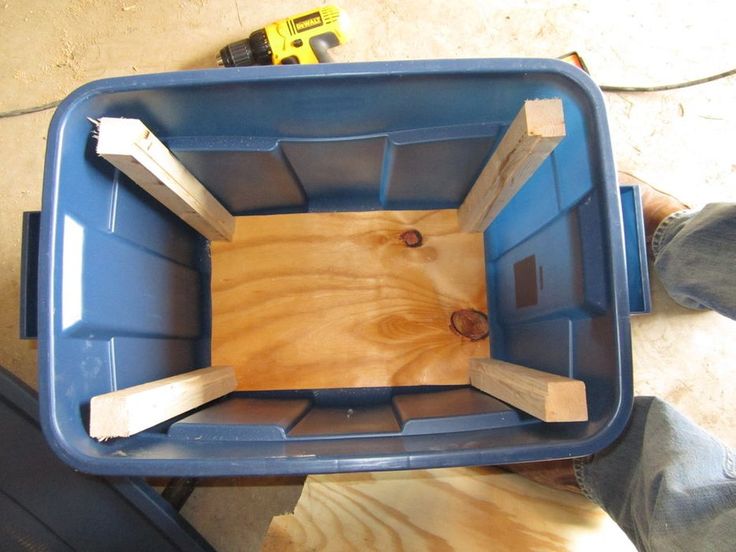 a person standing next to a blue container with wood in it's bottom compartment