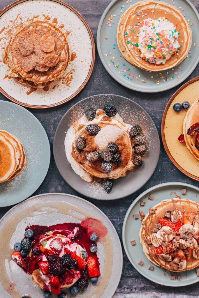 pancakes, waffles and fruit are arranged on plates