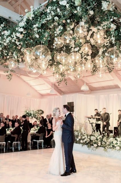 a bride and groom sharing their first dance at the wedding reception in front of an audience