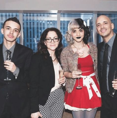 a group of people standing next to each other holding wine glasses and posing for the camera