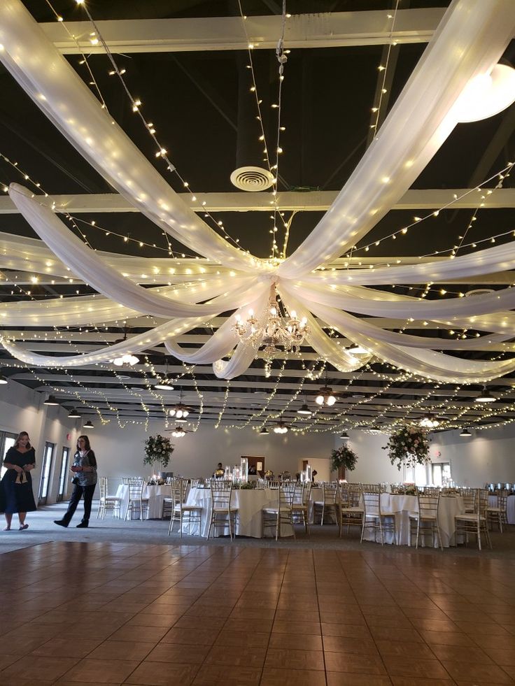 the ceiling is decorated with lights and white draping for an elegant wedding reception