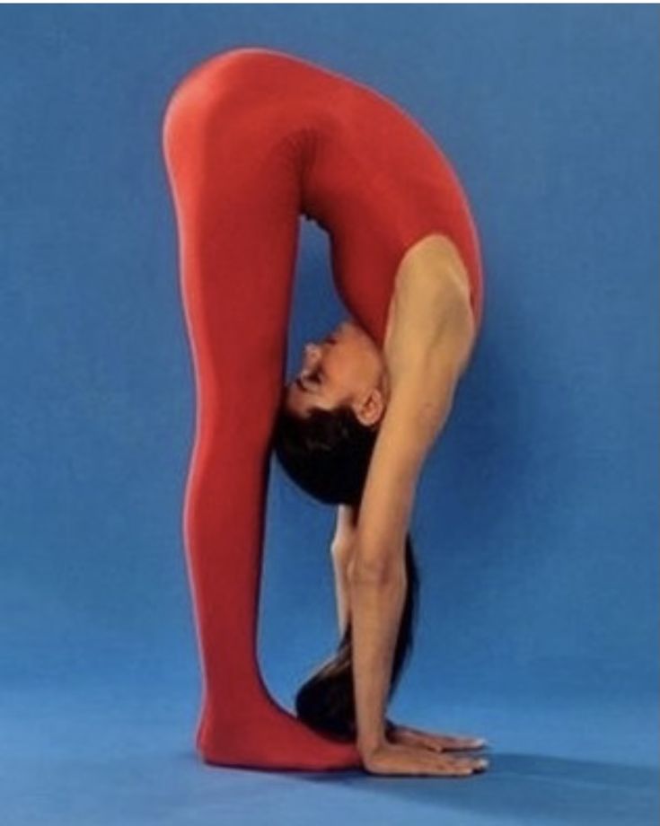 a woman in red and black doing a yoga pose with her hands behind her head