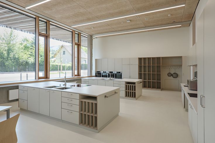 an empty kitchen with lots of counter space and large windows on the side of the room