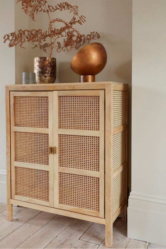 a wooden cabinet with wicker doors and metal vases on it's top