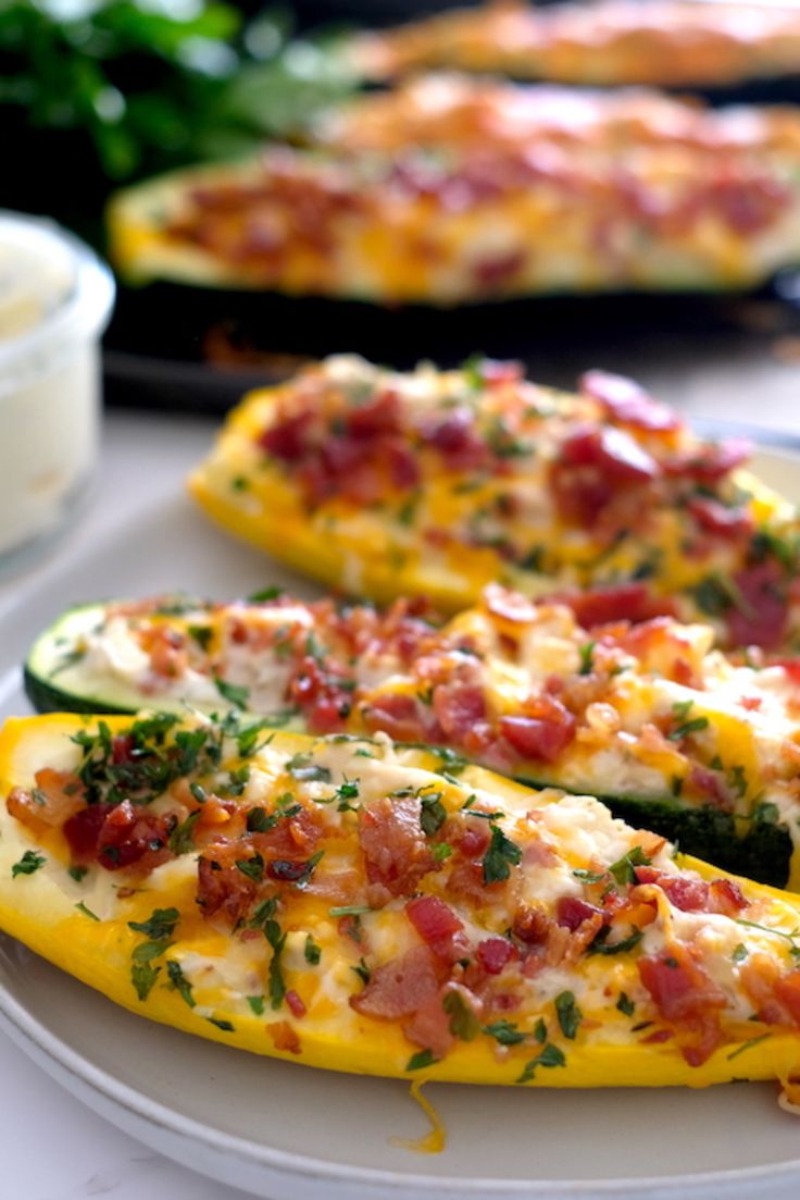 two stuffed yellow peppers with toppings on them sitting on a plate next to other food