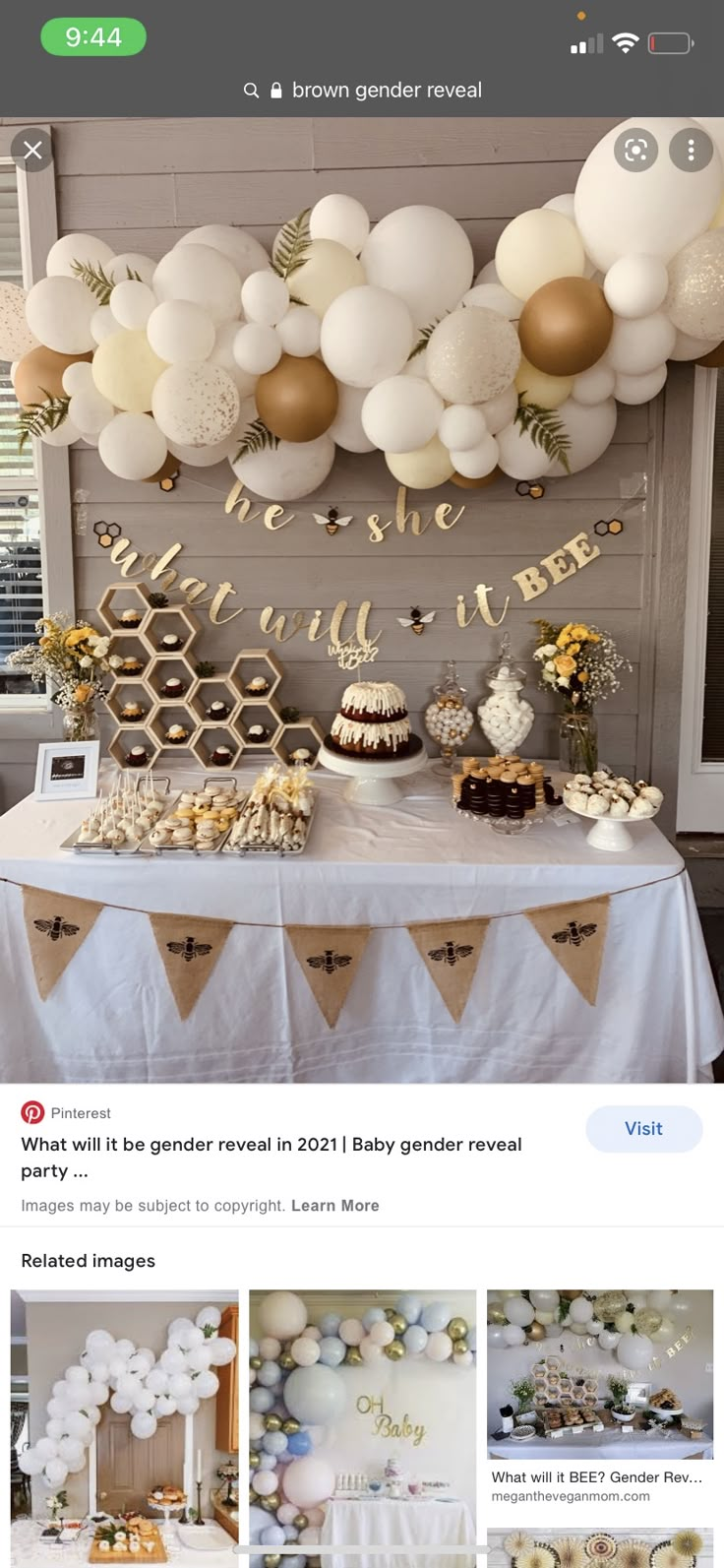 a table topped with lots of balloons and desserts next to a wall covered in white and gold decorations