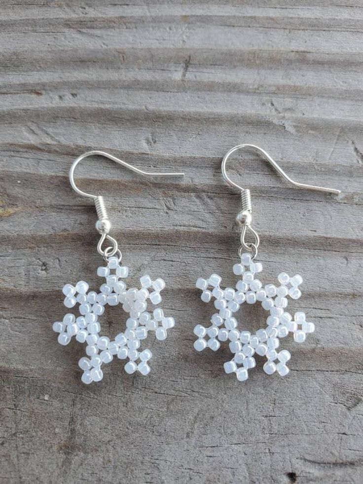 two snowflake earrings are shown on a piece of wood