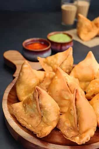 fried dumplings on a wooden plate with dipping sauces