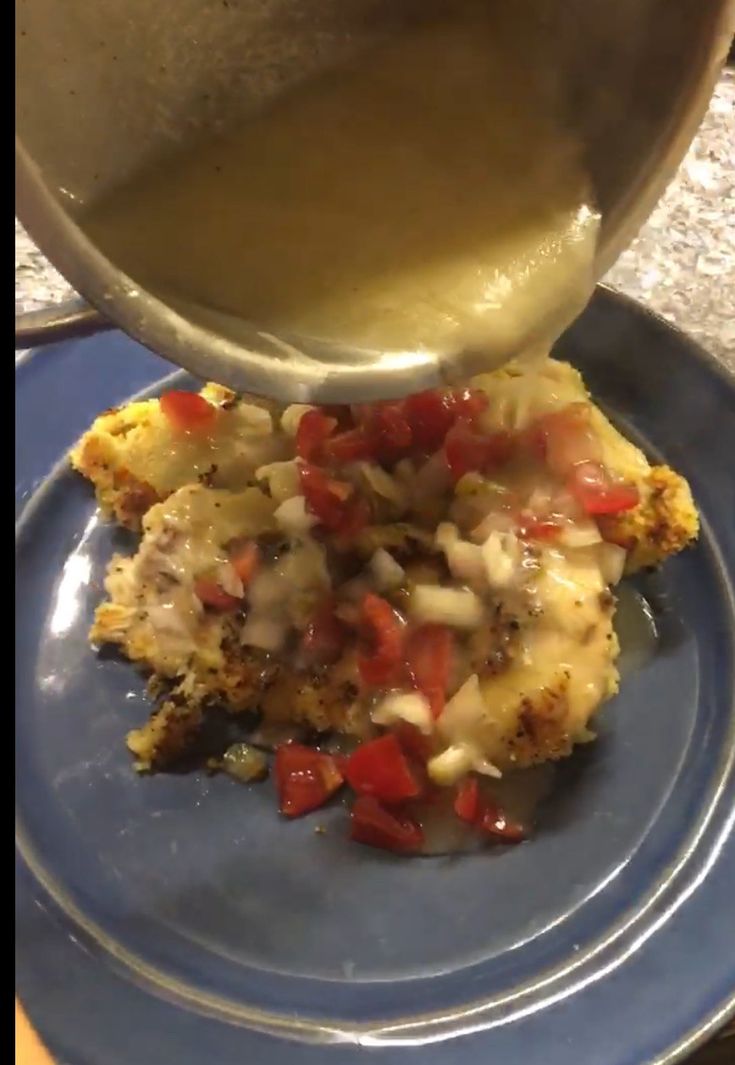 someone is pouring gravy over some food on a blue plate with a spoon