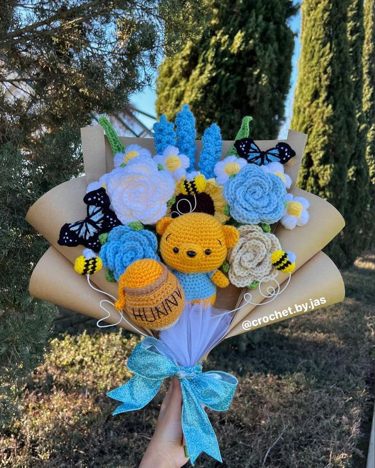 a person holding a bouquet of crocheted flowers and stuffed animals in their hands