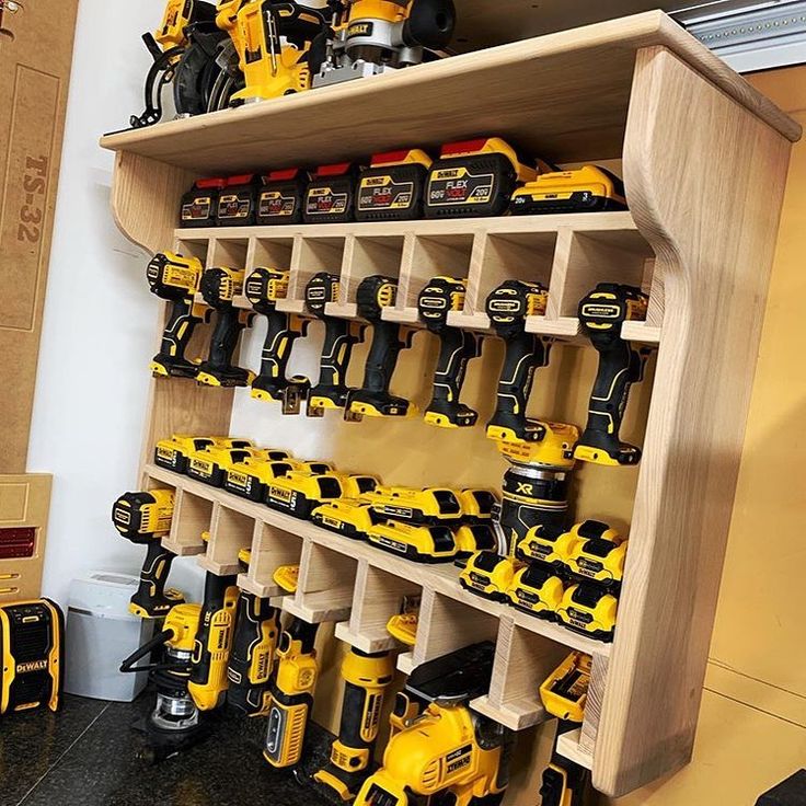 a wooden shelf filled with lots of yellow and black power drillers on top of each other