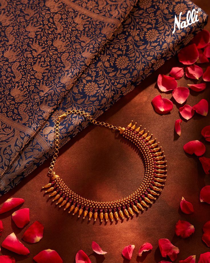 This traditional Kerala gold necklace is crafted in 22-karat gold in a mullu malai pattern with ruby stones and gold beads in two layers over the neckline. With the easy hook closure, this neckpiece is very easy and elegant to carry. Match this necklace with a silk saree, high heels, and bold lips to complete the look. Saree Ornaments Simple, Kerala Traditional Necklace, Kerala Necklace Designs, Elakkathali Necklace, Kerala Jewellery Necklaces, Neckpiece For Saree, Kerala Jewellery Traditional, Traditional Jewelry Kerala, Kerala Gold Jewellery