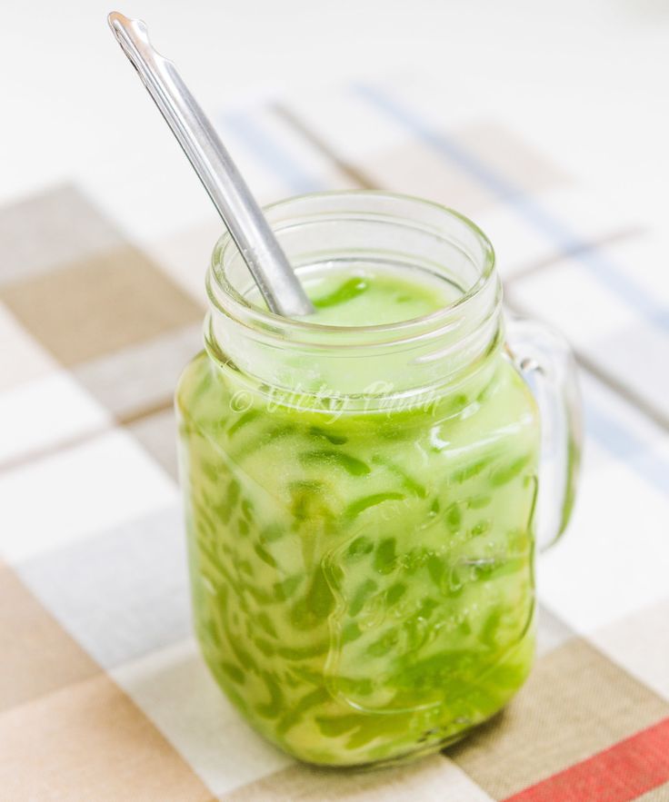 a glass jar filled with green liquid on top of a checkered table cloth