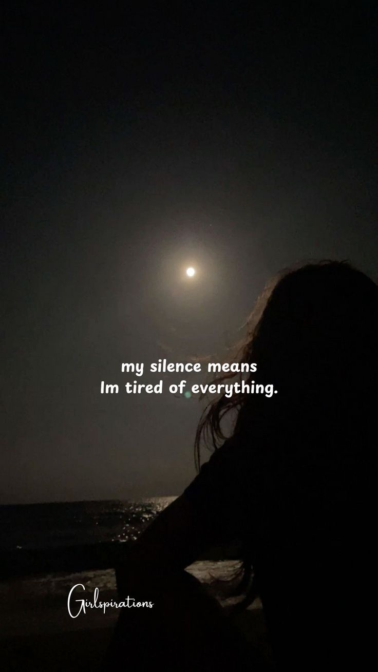 a person sitting on the beach at night with a full moon in the sky above them