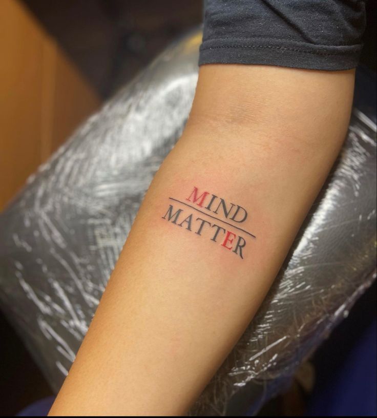 a person with a tattoo on their arm that says mind matter in red and black