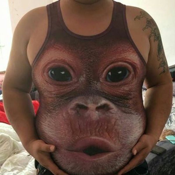 a man is holding up his shirt to show the face of an orangutan