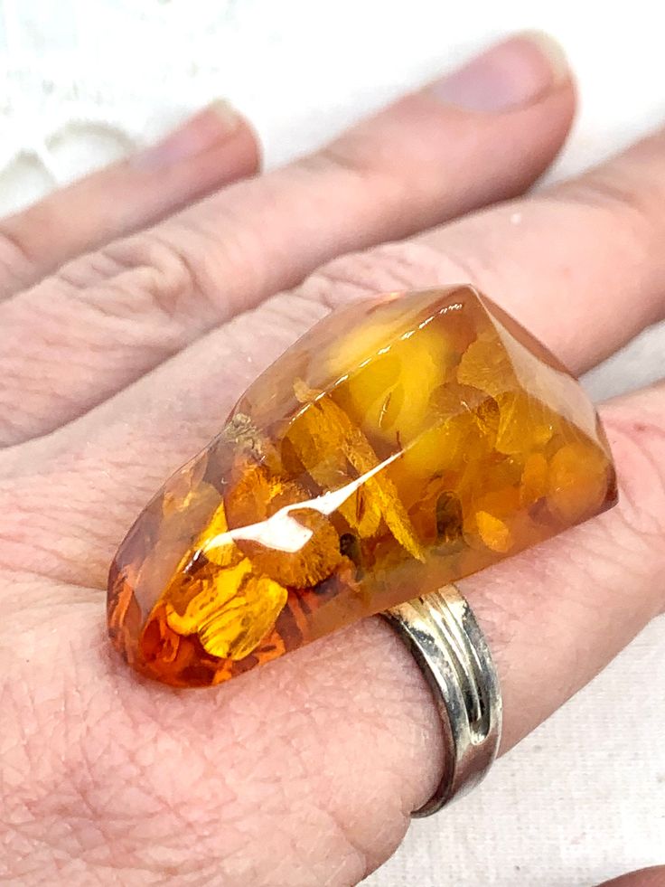 "Fabulous huge natural shape vintage Baltic amber ring. The amber is 1 1/4\"/ 4 cm long. The amber has lots of great inclusions, including reflective pieces, making this a real attention-getter! The band is adjustable - right now it is a size 7 but can be made bigger or smaller. I'm not sure of the metal type. Great condition.   Please note colours may vary depending on lighting, and your computer settings. If you have any questions please ask before purchase. I can combine shipping for multiple items - please message me prior to placing order." Elegant Amber Ring With Large Stone, Oval Baltic Amber Ring In Amber, Vintage Amber Jewelry With Polished Finish, Antique Hallmarked Amber Rings, Baltic Amber Ring, Attention Getters, Amber Heart, Yellow Gemstones, Amber Ring