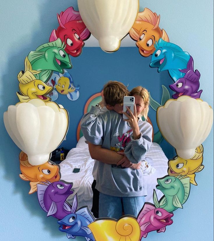 a woman taking a photo of herself in front of a mirror with fish on it