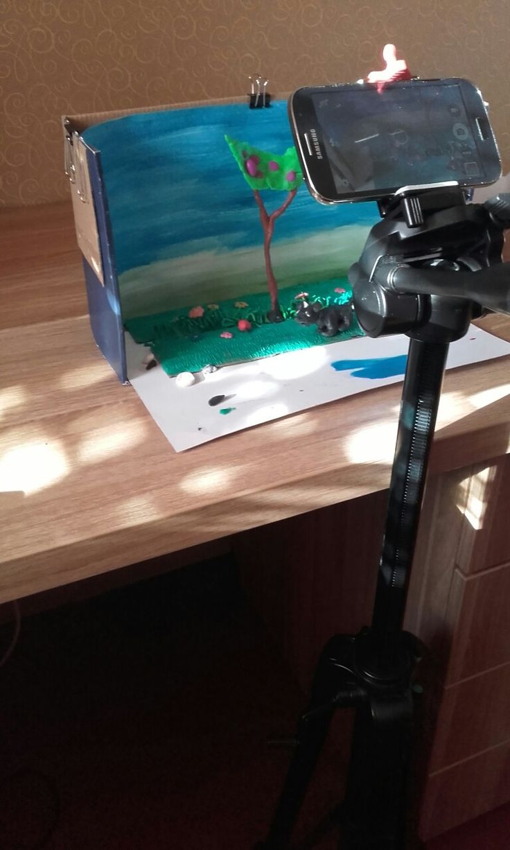 a cell phone is sitting on top of a tripod in front of a painting