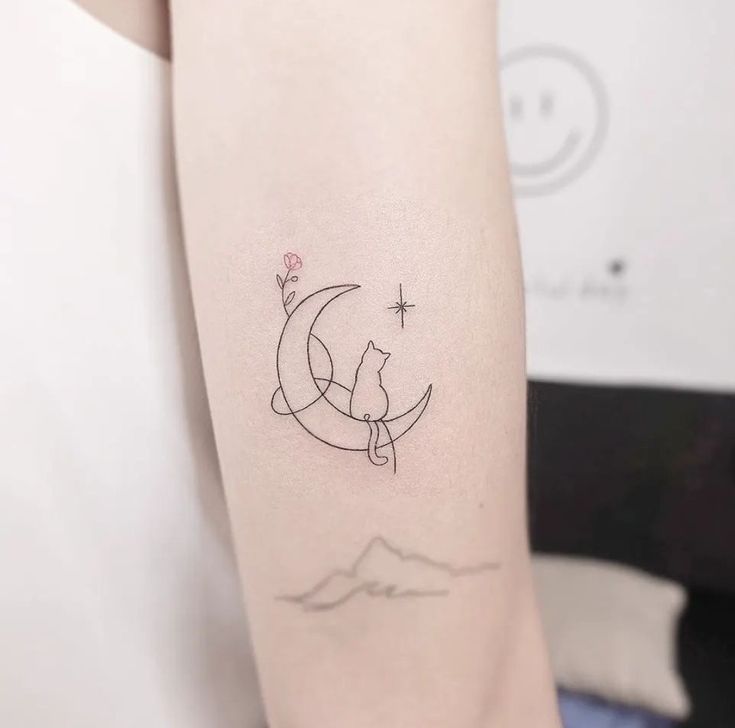 a cat sitting on the moon tattoo on the right arm and shoulder, with stars in the background