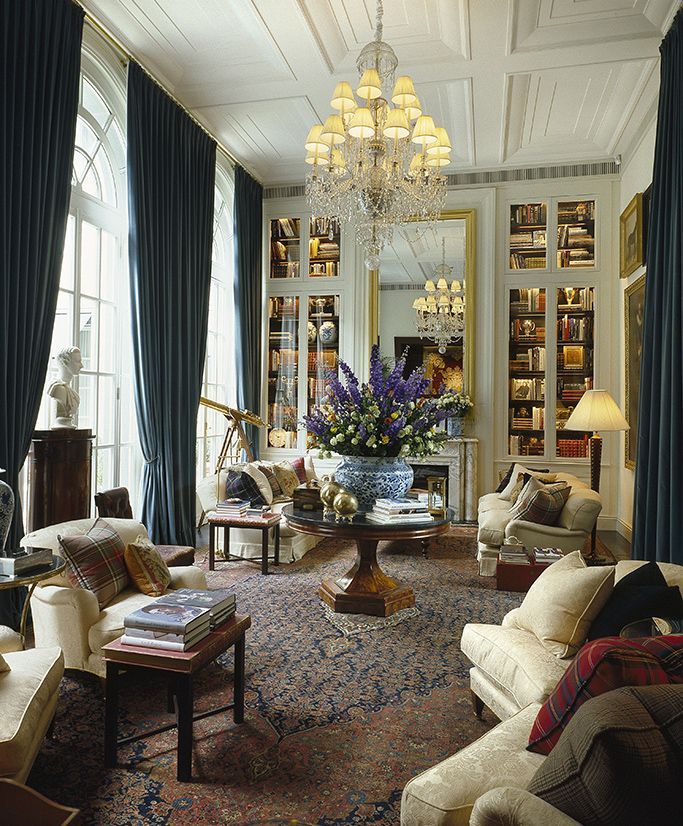 a living room filled with lots of furniture and a chandelier hanging from the ceiling