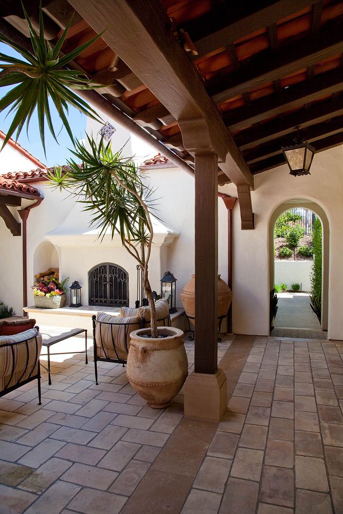 an outdoor living area with potted plants and seating on the patio, surrounded by stone pavers