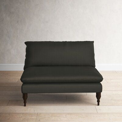 a black couch sitting on top of a hard wood floor next to a white wall