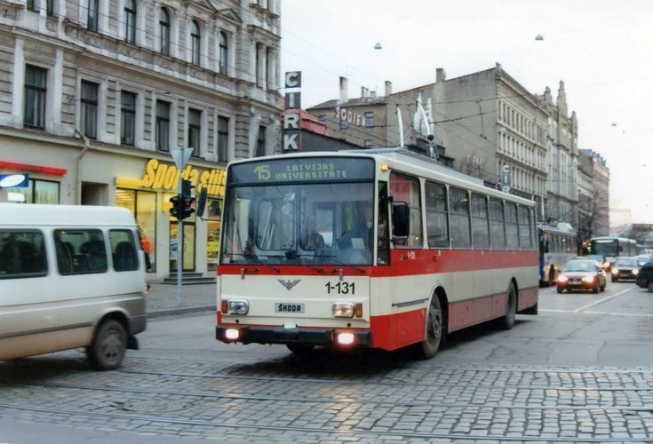 a red and white bus driving down a street next to tall buildings