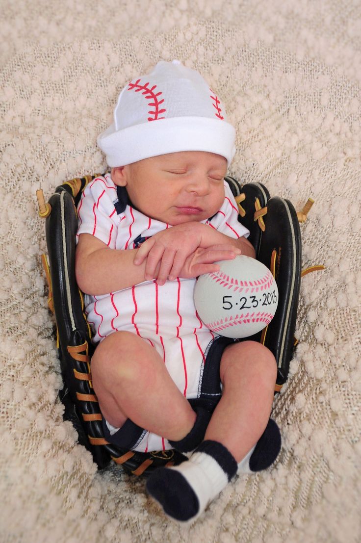 a baby is laying in a baseball mitt with a hat on it's head