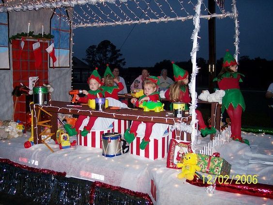 people dressed in elf costumes on top of a train with christmas decorations and lights around them