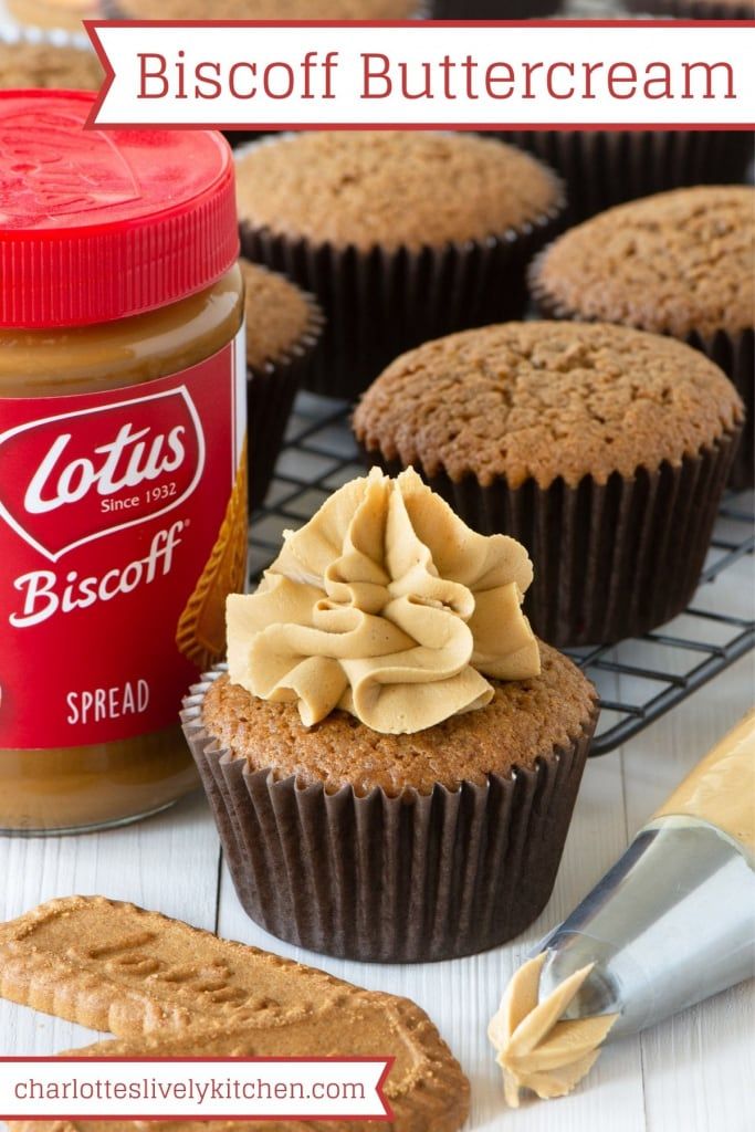 cupcakes with peanut butter frosting on a cooling rack next to a jar of biscuit butter