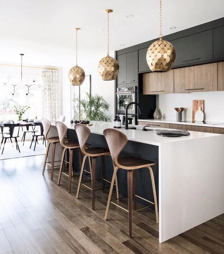 a kitchen with wooden flooring and white counter tops next to an island in front of a dining room table