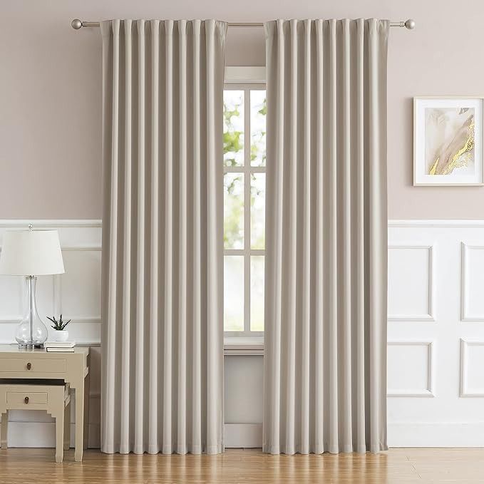 a living room with white walls and beige curtains on the window sill, along with a small table in front of it