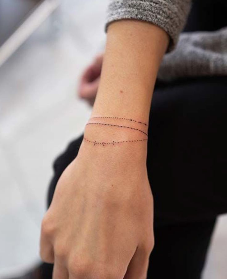 a woman's wrist with a thin line tattoo on it