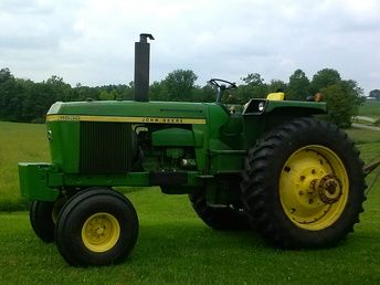 a green tractor parked on top of a lush green field