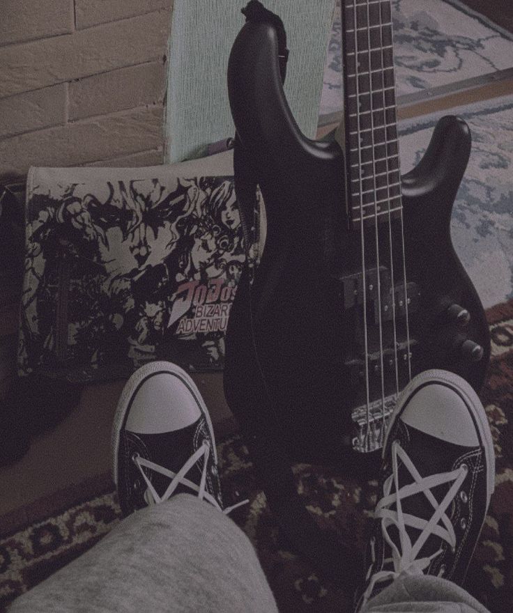 a person with their feet up next to a bass guitar