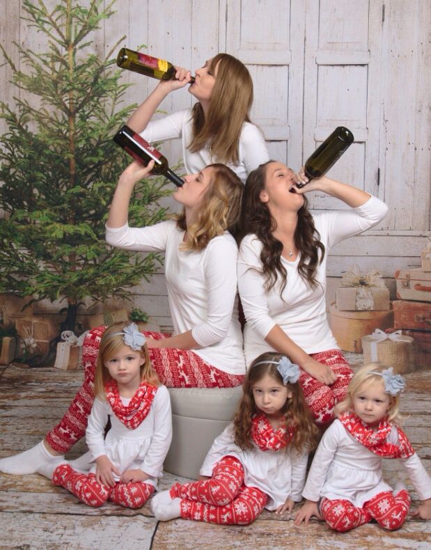 a group of women sitting next to each other on top of a wooden floor with bottles in their mouths