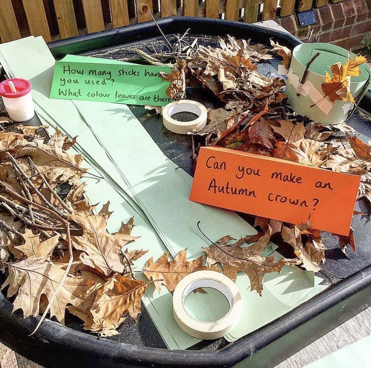 a trash can filled with lots of leaves and paper taped to the side that says can you make an autumn crown?