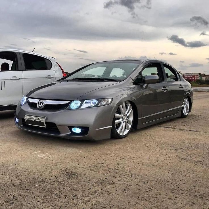 two cars parked next to each other in a parking lot with cloudy skies behind them