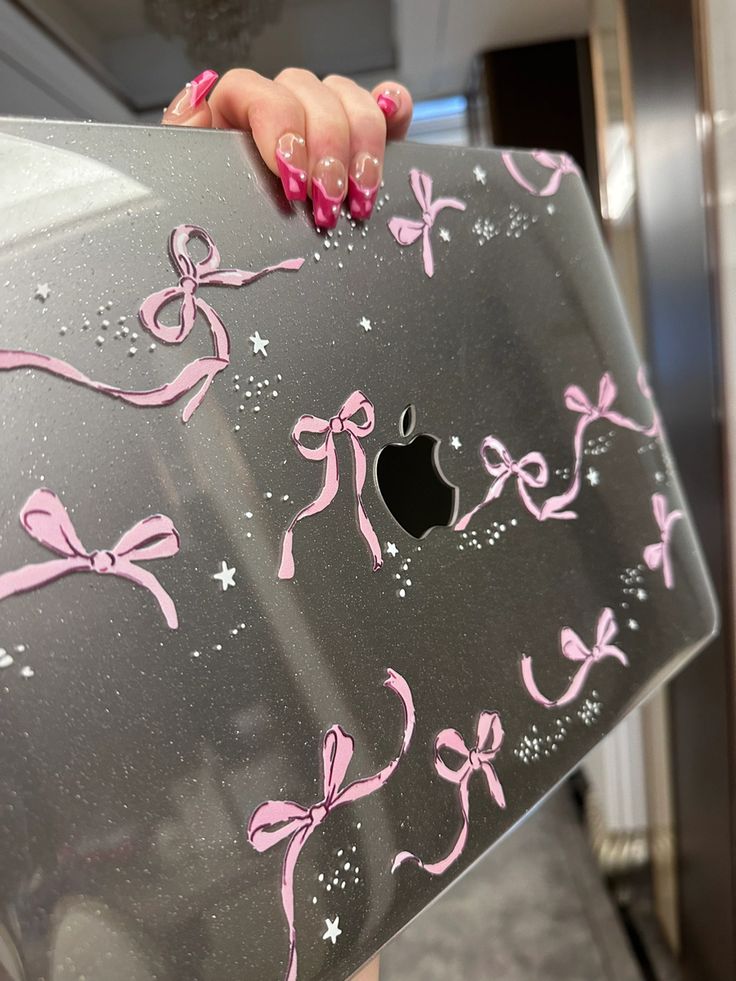 a woman holding an apple computer with pink bows on the side and stars in the back