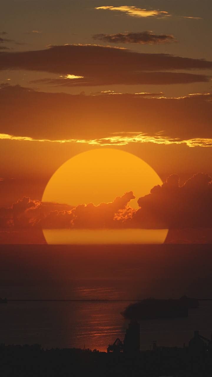 the sun is setting over the ocean with clouds in the sky and water below it