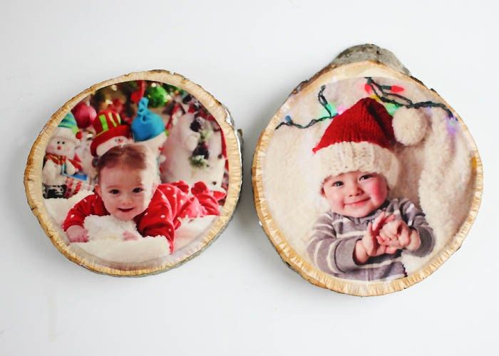 two wooden slices decorated with pictures of babies and santa hats, one is holding a baby's hand