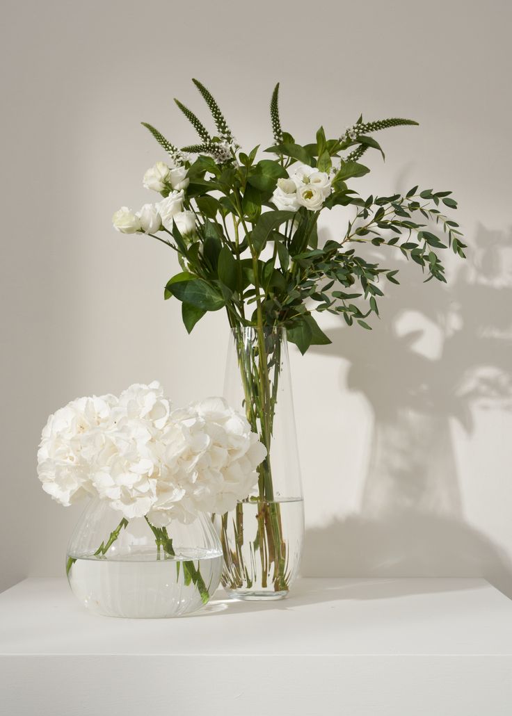 two vases filled with white flowers on top of a table