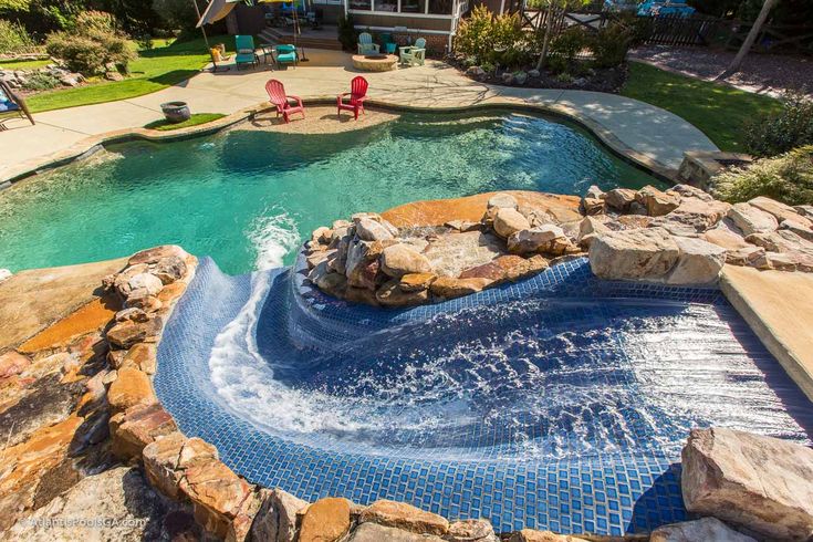 an image of a pool in the middle of a yard with rocks and water coming out of it