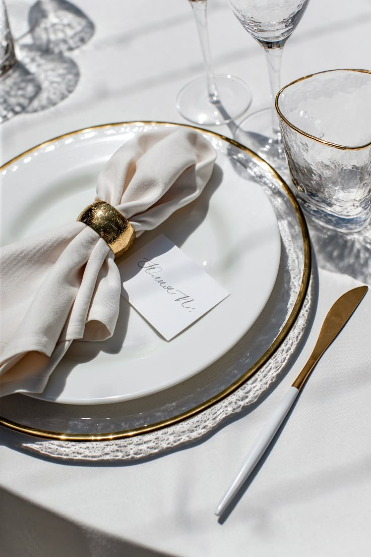 a white plate topped with a napkin next to glasses and utensils on top of a table