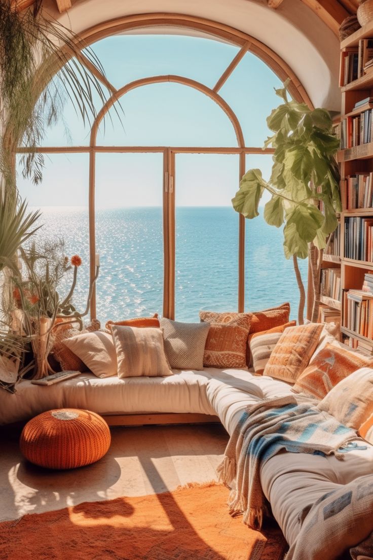 a living room filled with lots of furniture and bookshelves next to the ocean