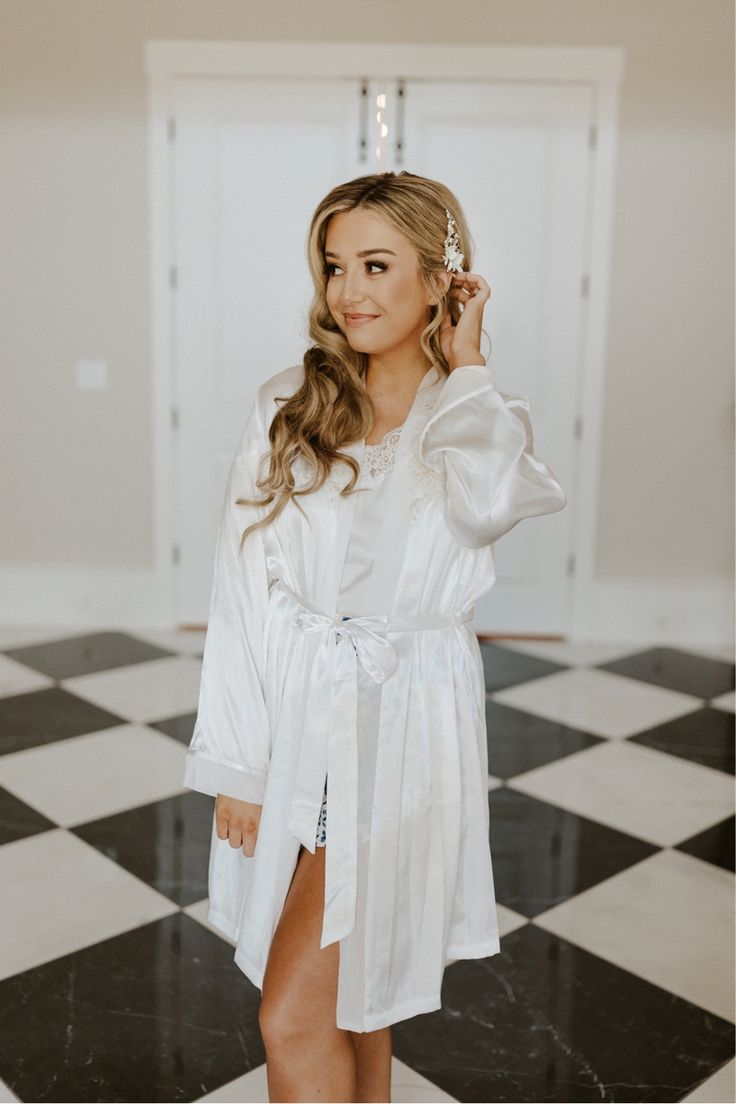 a woman in a white robe standing on a black and white checkered floor