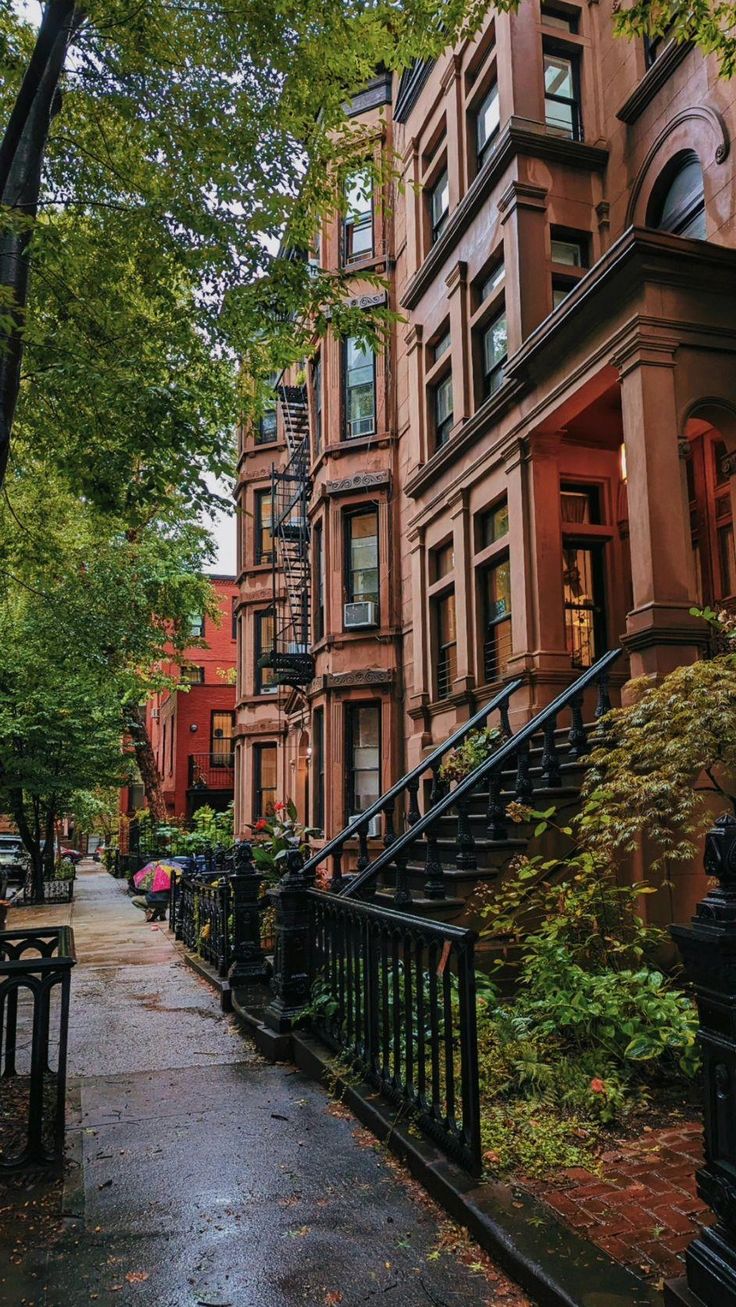 an alleyway with many brownstone buildings and trees