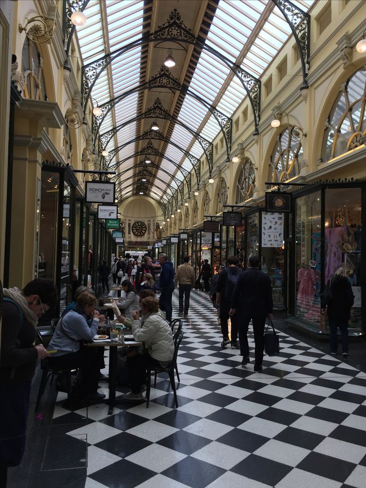 people are sitting at tables in the middle of an indoor shopping mall with high ceilings